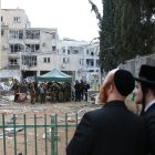 Dos hombres judíos ultraortodoxos cerca de una escuela de niñas judías dañada después de que misiles balísticos iraníes impactaran Bnei Brak, en el centro de Israel, el 16 de junio de 2025.