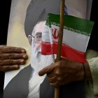 Un musulmán chiita pakistaní sostiene un retrato del líder supremo de Irán, Alí ​​Jamenei, y una bandera nacional de Irán durante una manifestación en solidaridad