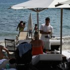 A waiter serves drinks to sunbathers sitting on their sunbeds along the beach on the Halkidiki Peninsula, northern Greece on June 13, 2025. After a year in which a record number of international tourist arrivals were recorded in Greece, more than 36 million people, and optimistic forecasts for 2025, thousands of jobs in tourism businesses remain vacant at the start of the tourist season. (Photo by Sakis Mitrolidis / AFP)
Personal. Un camarero sirve bebidas a los bañistas sentados en sus tumbonas a lo largo de la playa en la península de Halkidiki, en el norte de Grecia, en junio de 2025.