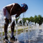 Un peatón en una fuente pública se vierte agua en la cara en un día caluroso en Berlín, Alemania, este miércoles 2 de julio de 2025.