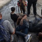 Palestinos ayudan a dos hombres heridos mientras intentaban recoger paquetes de alimentos, en la franja norte de Gaza, el 22 de junio de 2025.