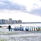 Personas caminan en una playa cubierta de nieve este lunes 30 de junio de 2025, en Miramar (Argentina).