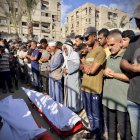 Personas rezan tras la llegada de los muertos bajo fuego israelí durante un bombardeo contra tiendas de campaña, en el sur de Gaza.