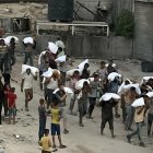 Hombres caminan cargando sacos de harina que fueron robados de un camión que transportaba alimentos, en Khan Yunis, en el sur de la Franja de Gaza, el 22 de julio de 2025.