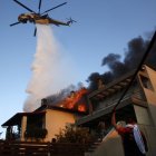 Un helicóptero de bomberos y voluntarios luchan para apagar un incendio que quema casas en la zona residencial de Kryoneri, en las afueras de Atenas, Grecia, este sábado 26 de julio.