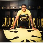 Erik Lamela frente a la bandera de su último club, el AEK Atenas de Grecia.