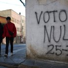 Personas caminan junto a un mural con un mensaje alusivo a la elecciones este sábado, en La Paz (Bolivia).