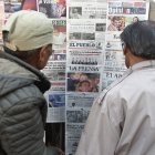 Dos personas leen periódicos con cobertura en portada de las elecciones presidenciales de Bolivia en un quiosco, en La Paz, el 18 de agosto de 2025.