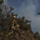 Un helicóptero de la lucha contra el fuego vuela sobre un bombero que trabaja en la extinción del incendio.(Lugo, Galicia).