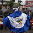 Joven con una bandera de Nicaragua frente a Policías, en Managua (Nicaragua).
