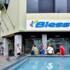 Usuarios del Banco del Instituto Ecuatoriano de Seguridad Social (Biess) y ciudadanía en general se sientan en el borde de una pileta ante la escasez de espacios adecuados.