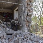 Un adulto mayor que se negó a evacuar, sentado entre los escombros de un edificio dañado, mientras los miembros de "Ángeles Blancos" ayudan a evacuar de la ciudad de Kostiantynivka.