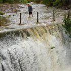 Un hombre cruza un badén inundable durante este lunes en el que el aviso rojo (riesgo extremo). España.