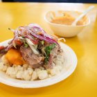 El hornado, un plato insignia de la ciudad que combina papa, choclo, mote, salsa criolla y ají casero.