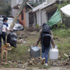 Personas caminan con sus pertenencias en una zona afectada por las fuertes lluvias el 12 de octubre de 2025, en Huauchinango (México).