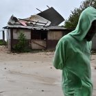 Una persona camina frente a una casa afectada por los vientos preliminares del huracán Melissa, en la playa pesquera de Hellshire, en Portmore (Jamaica).