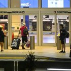 Los viajeros arrastran sus maletas mientras buscan un lugar donde esperar en el Aeropuerto Internacional de Orlando en Orlando, Florida.