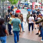 Varias personas, entre niños, tratan de convencer a los electores a que plastiquen con ellos el certificado de votación.