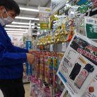Un empleado clasifica campanillas junto a un anuncio de spray para osos en una tienda de Hanamaki, prefectura de Iwate, el 24 de octubre de 2025.