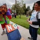 Una persona disfrazada sostiene una maleta mientras un hombre lo observa durante una manifestación contra el referéndum en Quito (Ecuador).