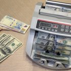 Una ilustración muestra una máquina contando billetes de pesos argentinos junto a billetes de dólares estadounidenses en Buenos Aires el 22 de octubre de 2025.