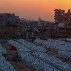 El sol se pone tras las ruinas de edificios destruidos y filas de tiendas de campaña de familias desplazadas en la Franja de Gaza, el 18 de noviembre de 2025.