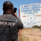 Un miembro de las fuerzas de seguridad toma fotografías del letrero de la Escuela Católica Privada St. Mary"s en Papiri, estado de Níger, Nigeria