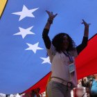 Una mujer camina debajo de una bandera durante la marcha "por la paz y la libertad" en Venezuela.