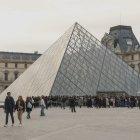 Vista del museo del Louvre de París en Francia, que aparece rodeado de turistas.