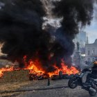 Un motociclista hace un wheelie pasando por un montón de neumáticos en llamas durante una protesta de agricultores en Bruselas, Bélgica, 18 de diciembre de 2025.