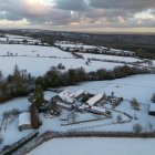 La imagen muestra un paisaje rural cubierto de nieve y edificios agrícolas en el Reino Unido durante una importante ola de frío a inicios de 2026.