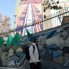 Un hombre iraní camina junto a una valla publicitaria antiestadounidense e israelí con un mensaje del secretario del Consejo Supremo de Seguridad Nacional, Ali Larijani, que dice "Cuidado con sus soldados".