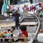 Hecho. Menores migrantes juegan sobre la vía de un campamento, en Ciudad de México (México), entre muros de madera, lonas y otros materiales reciclados.