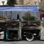 Iraníes caminan cerca de los restos de un autobús público incendiado en Teherán, Irán, el 15 de enero de 2026.