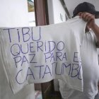 Un hombre desplazado por la violencia mostrando una camiseta con una nota escrita pidiendo paz para el Catatumbo en Cúcuta (Colombia).