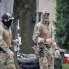 Agentes enmascarados del Servicio de Inmigración y Control de Aduanas (ICE) caminando frente a la entrada del centro de detención (Estados Unidos).