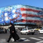 Una mujer iraní con velo camina cerca de un enorme cartel antiestadounidense colgado en la plaza Enqelab en Teherán, el sábado 31 de enero de 2026.