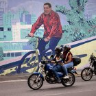 Motociclistas transitando frente a un mural del fallecido presidente de Venezuela, Hugo Chávez, este lunes 2 de febrero de 2026, en Caracas (Venezuela).