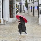 Una vecina de Grazalema (Cádiz) camina por una calle inundada debido a las intensas lluvias.