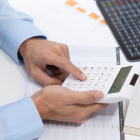 Referencial.Una persona revisa documentos financieros y utiliza una calculadora, en el marco de los requisitos para acceder al crédito Emprende Violeta de 500 dólares.