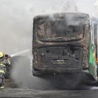 Un integrante del Cuerpo de Bomberos de Guadalajara intenta apagar un vehículo incendiado este domingo 22 de febrero, en esa ciudad mexicana.