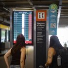 Dos pasajeras observan una pantalla informativa que muestra los vuelos cancelados en el Aeropuerto Internacional Jorge Newbery de Buenos Aires.