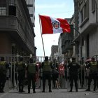 Policías hacen guardia mientras la gente protesta con una bandera nacional peruana afuera del edificio Faustino Sánchez Carrión del poder legislativo.