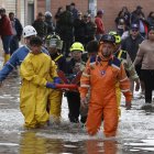 Integrantes de organismos de rescate socorren a un hombre en una calle inundada por fuertes lluvias este jueves, en Facatativá (Colombia).