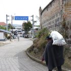 Un hombre carga un costal con productos agrícolas y lo atraviesa hasta cruzar el paso fronterizo.