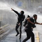 Manifestantes e integrantes de la Policía de antidisturbios de Carabineros de Chile se enfrentan durante una manifestación el 26 de marzo de 2026, en Santiago (Chile).