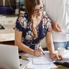 Una persona pone por escrito sus ingresos y apunta todo lo que tiene que pagar.