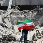 “Un ciudadano sostiene la bandera de Irán en medio de los escombros tras recientes ataques.