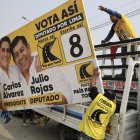 Personas sostienen una valla publicitaria del candidato a la Presidencia de Perú Carlos Álvarez y el diputado Julio Rojas este sábado, en Lima (Perú).