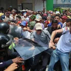 Personas exigen aumentos salariales mientras se enfrentan con integrantes de la policía en una manifestación este jueves, en Caracas (Venezuela).